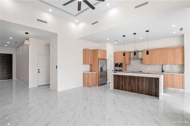 a large kitchen with stainless steel appliances kitchen island a large counter top and wooden floors