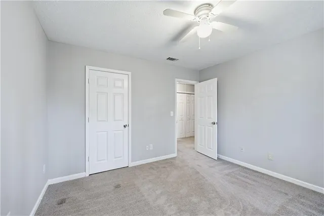an empty room with chandelier fan and closet area