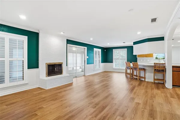 a view of an empty room with wooden floor and a fireplace
