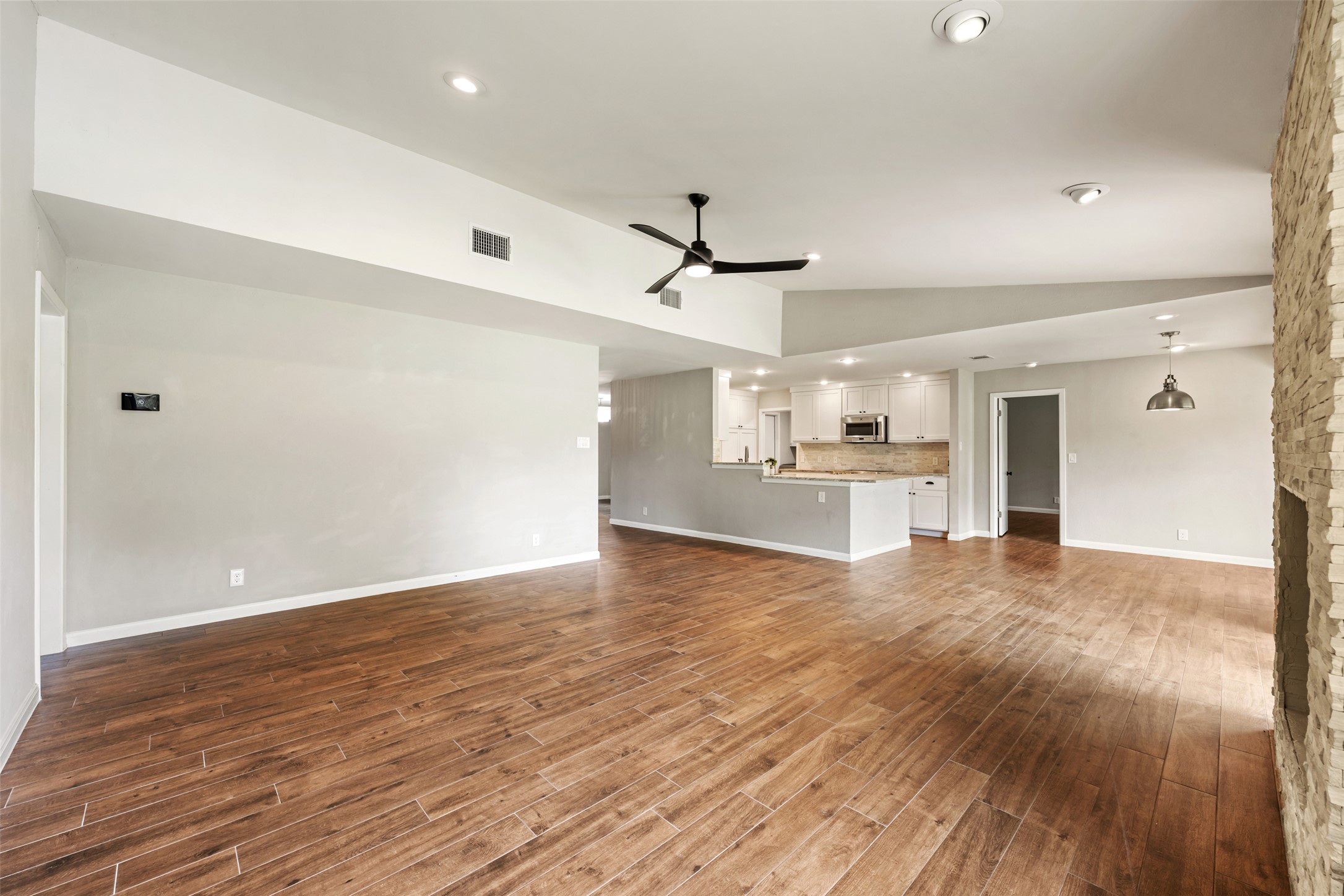 1600 Pin Oak Lane Round Rock, TX 78681 - Photo 14 of 40 Expansive open-concept living area featuring wood-finish flooring, a vaulted ceiling with recessed lighting and a ceiling fan, and a stone-clad fireplace