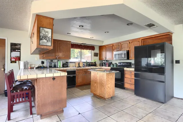 a kitchen with stainless steel appliances granite countertop a refrigerator a stove top oven and a sink