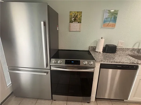 a kitchen with granite countertop a refrigerator stove and sink