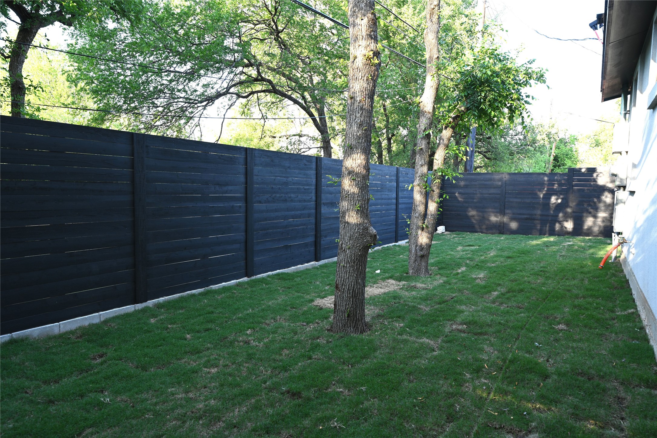 4410 Glomar Avenue, Unit 2 Austin, TX 78721 - Photo 23 of 24 The backyard features a well-maintained lawn, mature trees, and a dark-toned privacy fence
