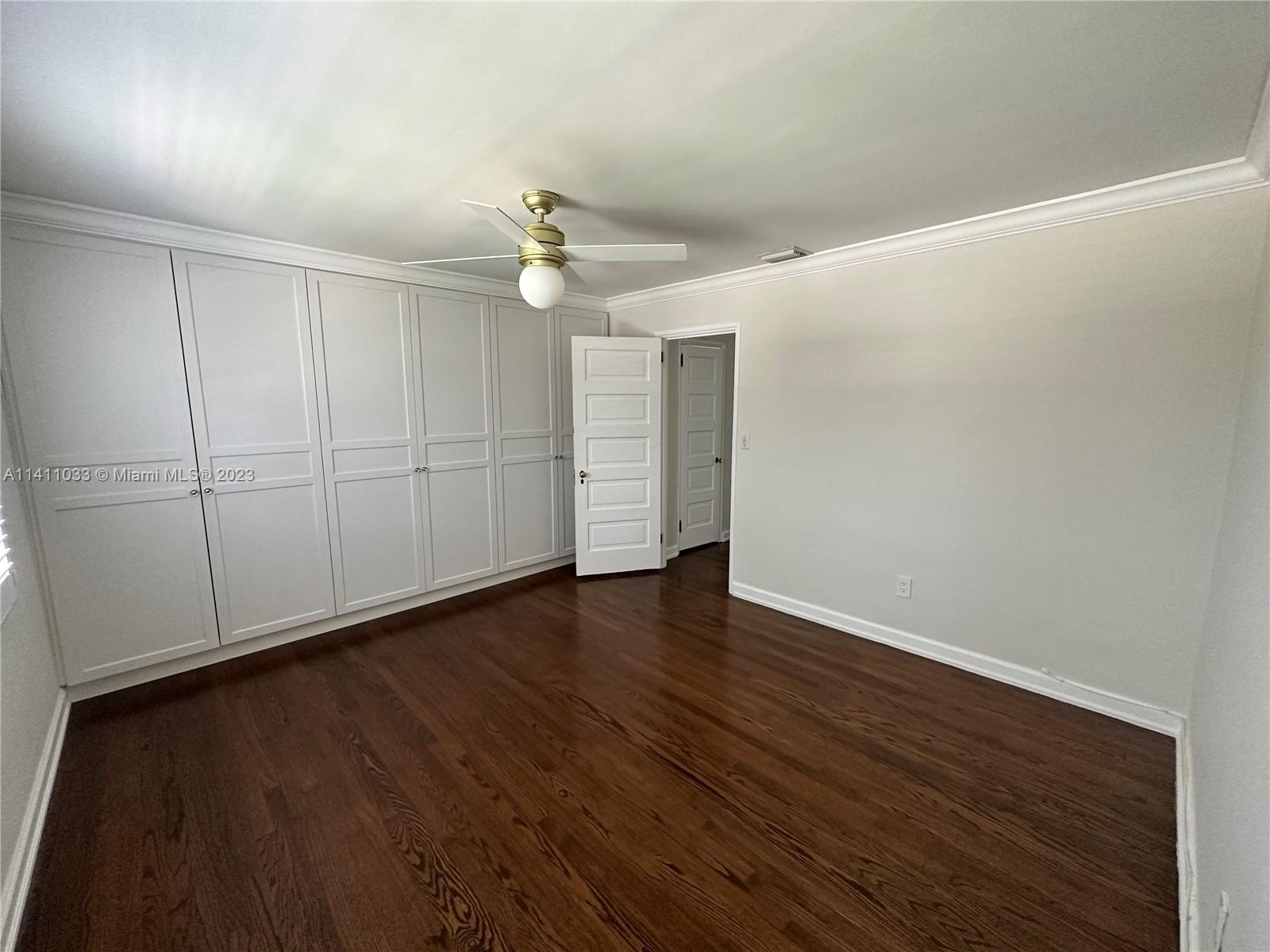 Mid Beach Miami Beach, FL 33140 - Photo 14 of 40 an empty room with wooden floor chandelier fan and windows