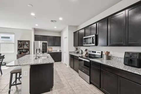 a kitchen with granite countertop a refrigerator and a stove top oven