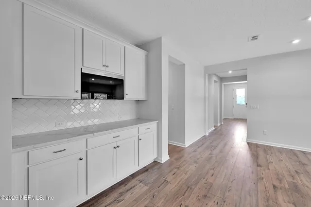 a view of a kitchen with wooden floor and electronic appliances