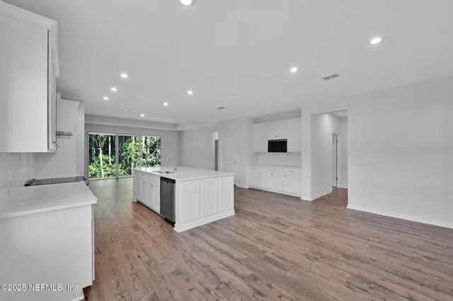 a large white kitchen with wooden floors and white stainless steel appliances