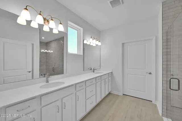 a bathroom with a double vanity sink mirror and chandelier