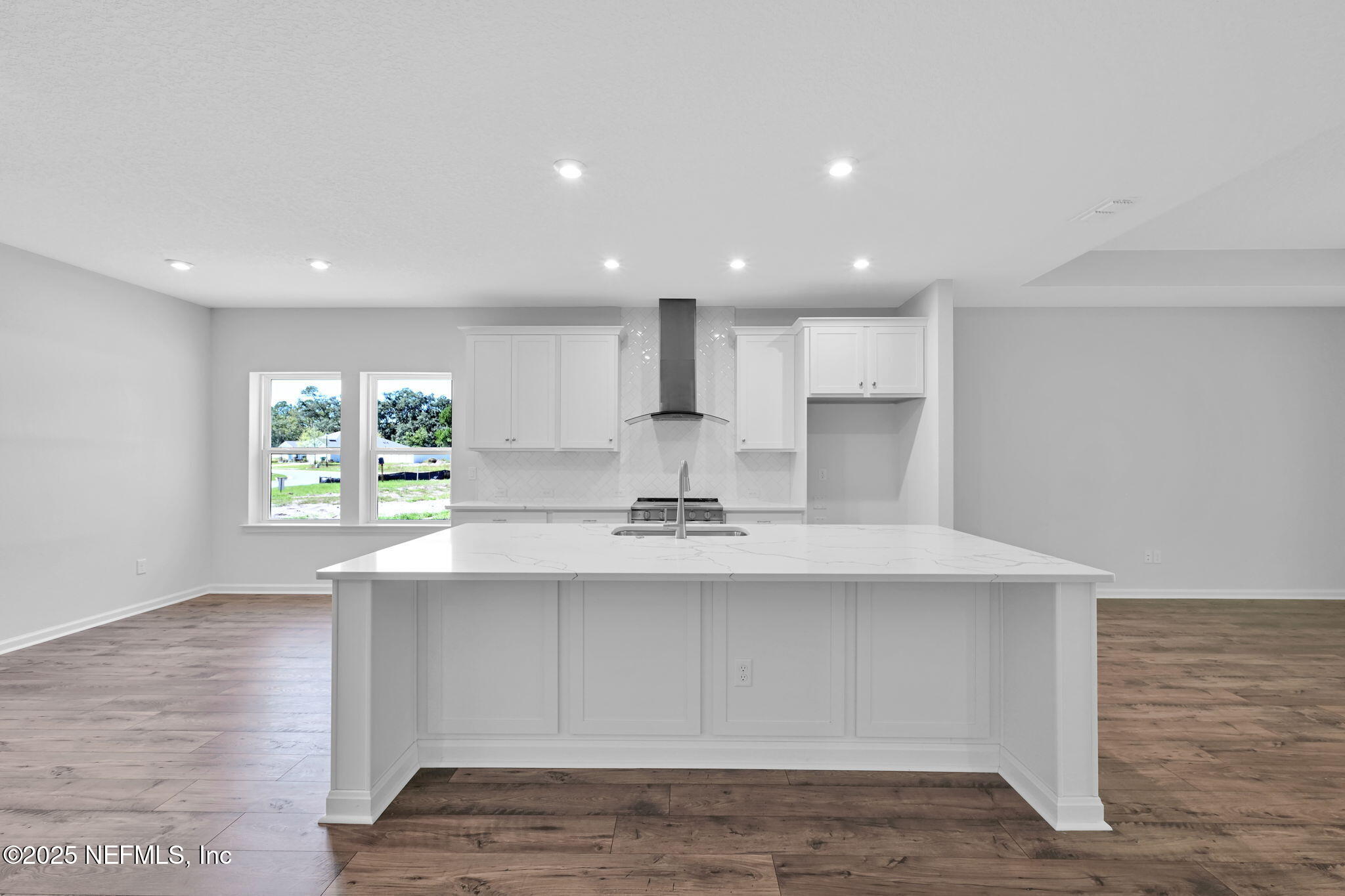 97003 Mcgirts Creek Loop Yulee, FL 32097 - Photo 9 of 40 a view of a kitchen with kitchen island a sink wooden floor and a refrigerator