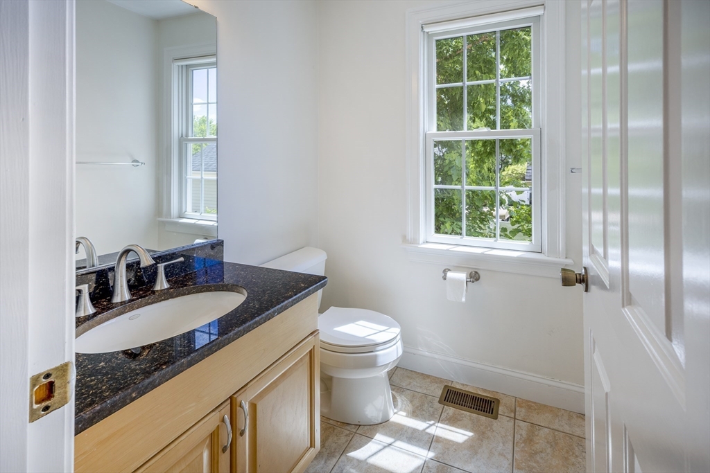 54 Spruce Street Winchester, MA 01890 - Photo 12 of 29 a bathroom with a granite countertop toilet a sink and a mirror
