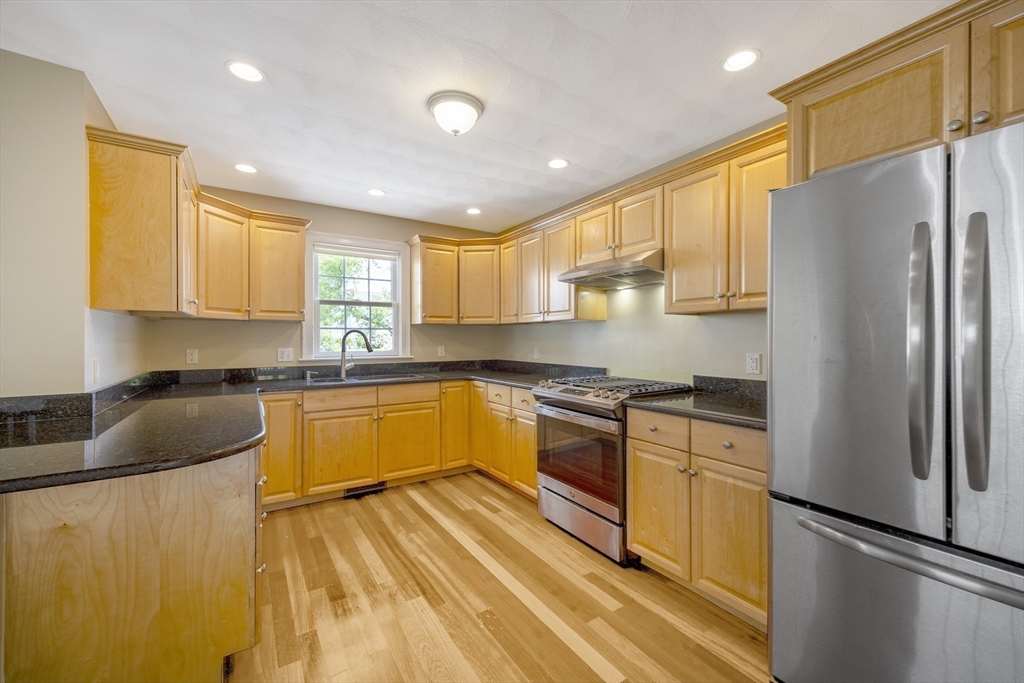 54 Spruce Street Winchester, MA 01890 - Photo 2 of 29 a kitchen with stainless steel appliances granite countertop a refrigerator a sink dishwasher a stove and white countertops with wooden floor
