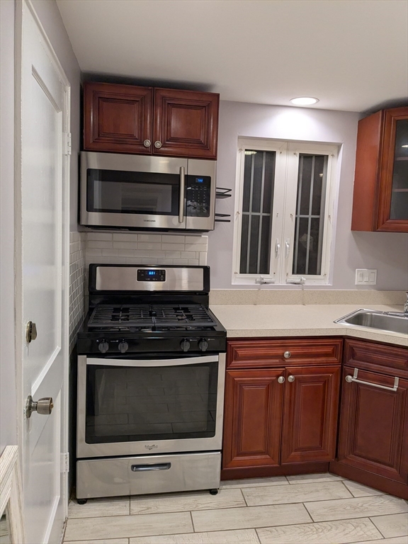 33 Paragon Road, Unit 1 Boston, MA 02132 - Photo 16 of 18 a kitchen with granite countertop stainless steel appliances and wooden cabinets