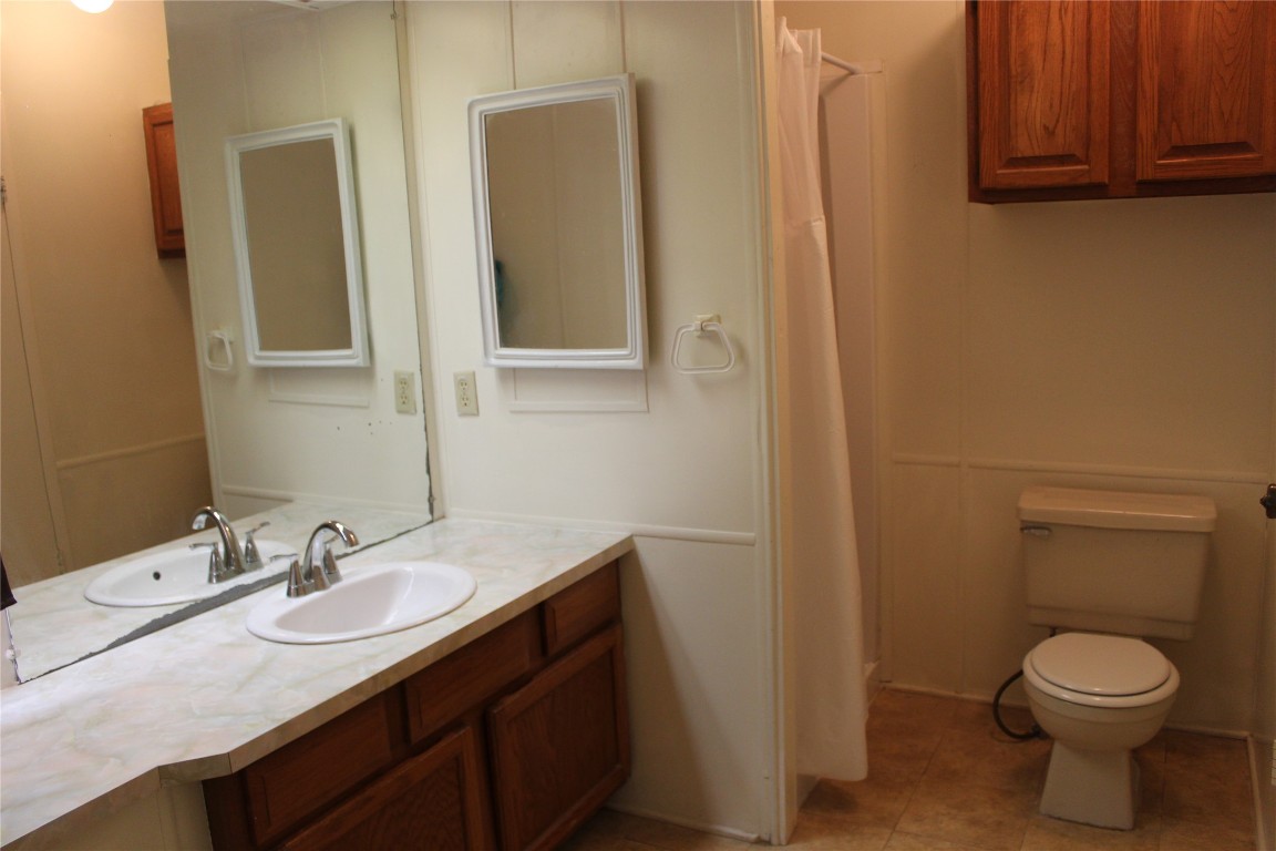 14111 South Green Hills Loop, Unit B Austin, TX 78737 - Photo 9 of 13 a bathroom with a granite countertop sink toilet and mirror