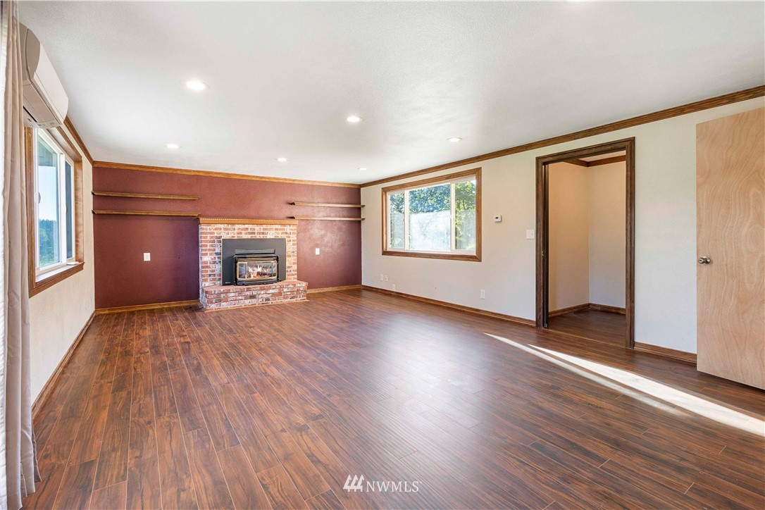 10101 James Road Southwest Rochester, WA 98579 - Photo 15 of 34 a view of empty room with a fireplace and wooden floor