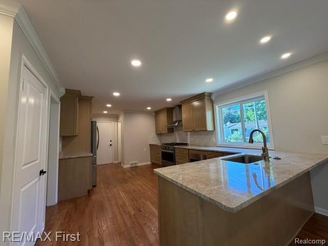 971 Canterbury Road Grosse Pointe, MI 48236 - Photo 14 of 30 Kitchen featuring wood-finish flooring, recessed lighting, crown molding, and an island with an undermount sink and stone countertop