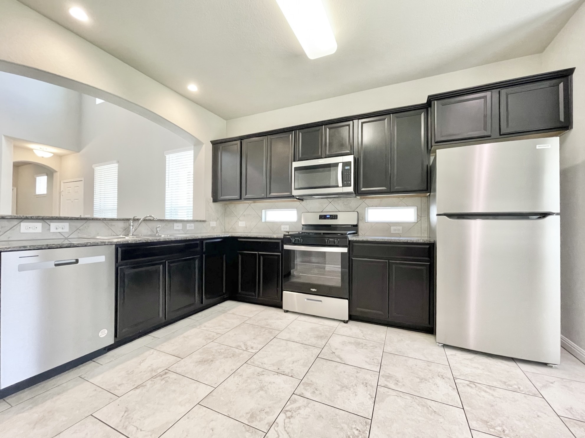 407 Rhetoric Way Pflugerville, TX 78660 - Photo 12 of 38 a kitchen with granite countertop a refrigerator and a stove top oven