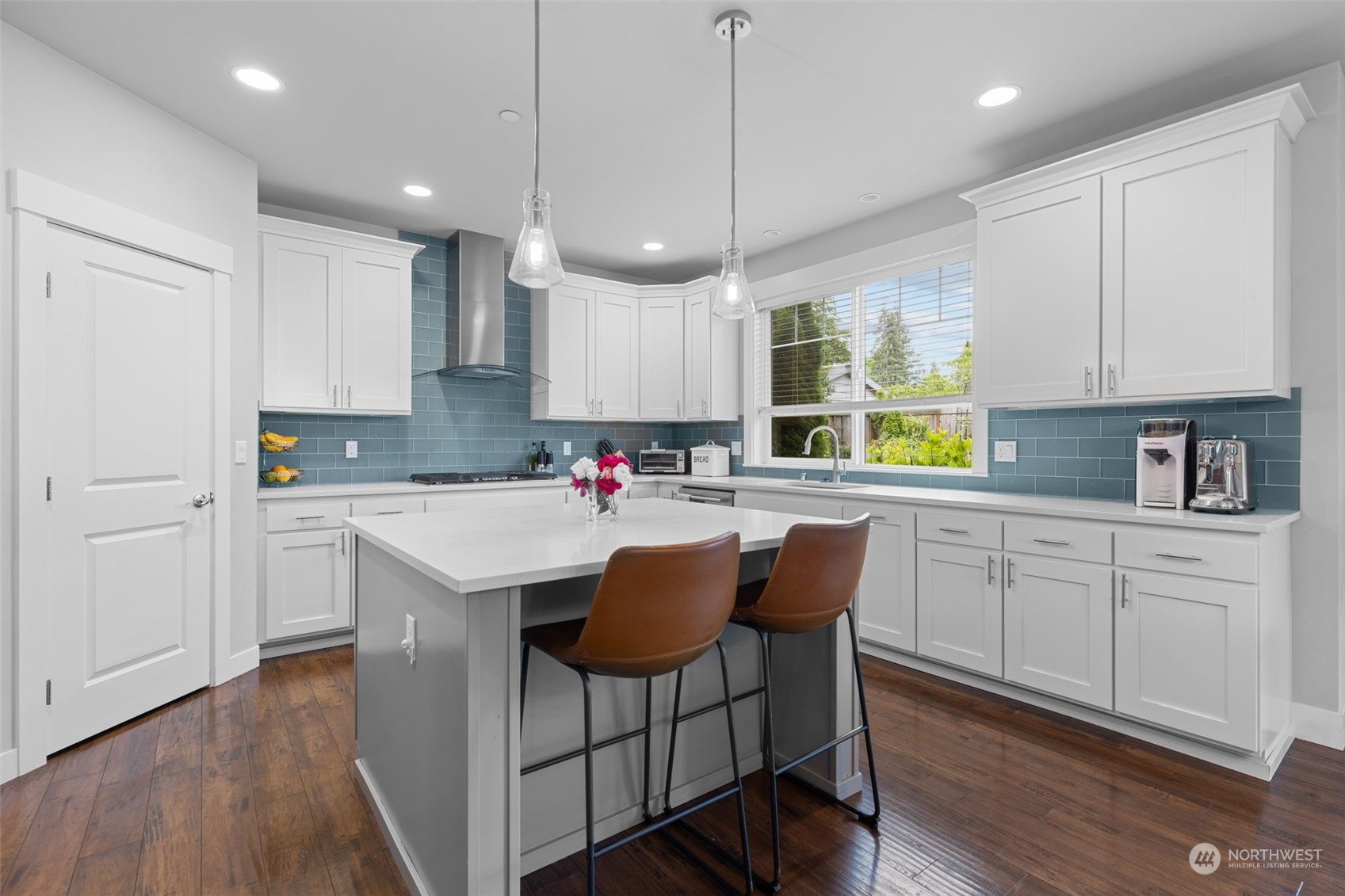 21815 86th Place West Edmonds, WA 98026 - Photo 9 of 25 a kitchen with stainless steel appliances granite countertop white cabinets a refrigerator a sink a stove a dining table and chairs with wooden floor