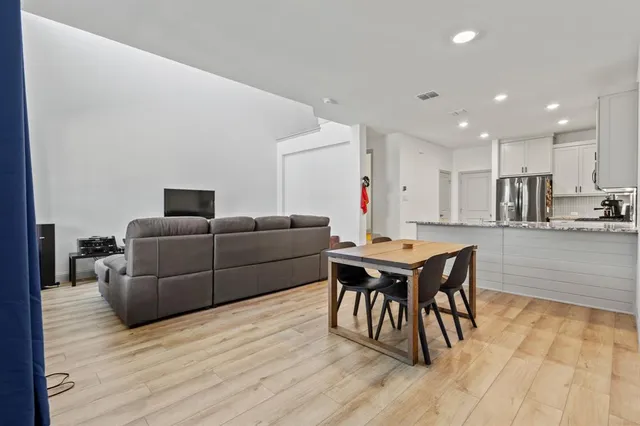 a living room with furniture a wooden floor and a kitchen view