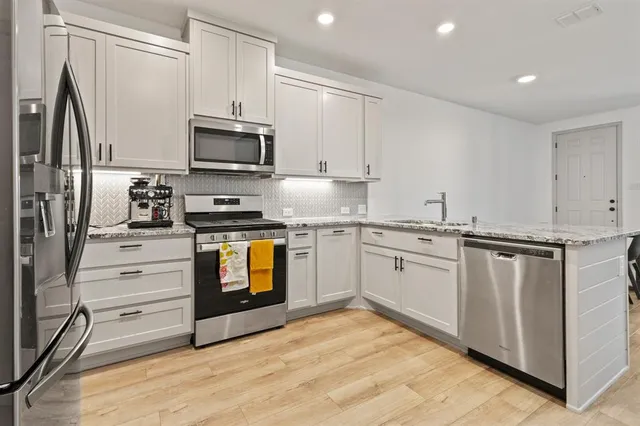 a kitchen with granite countertop a refrigerator stove and microwave