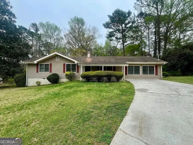 a front view of house with a garden and trees
