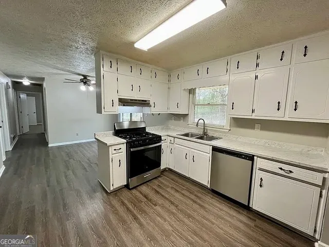 a kitchen with granite countertop a sink cabinets and stainless steel appliances