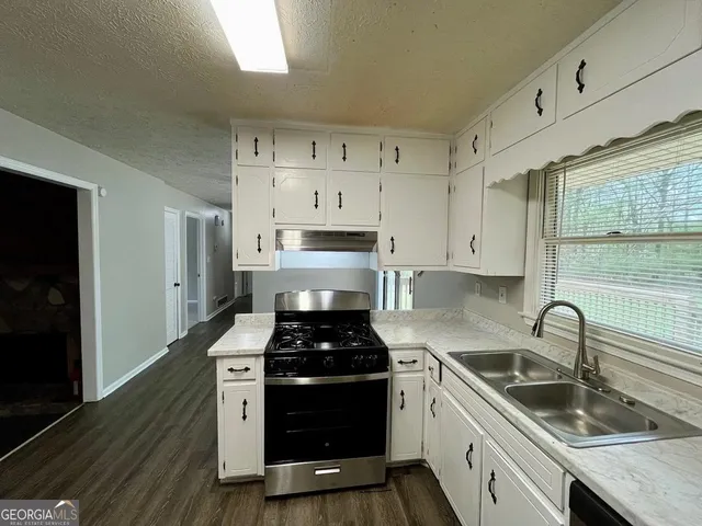 a kitchen with granite countertop a sink stainless steel appliances and cabinets