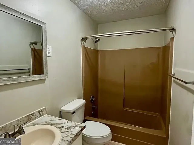 a bathroom with a shower a toilet and a sink