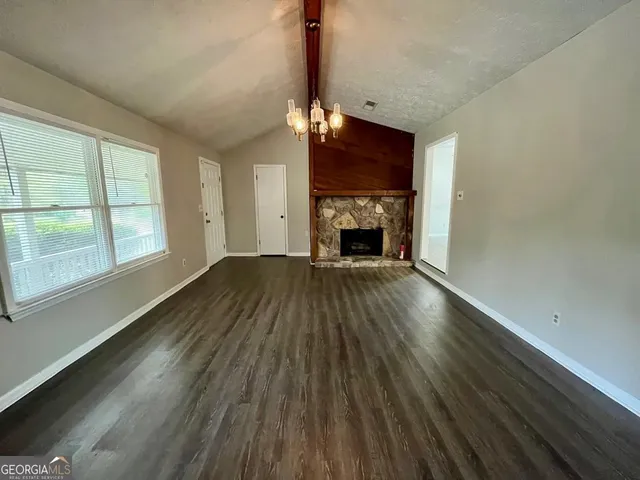 a view of empty room with wooden floor fireplace and a window