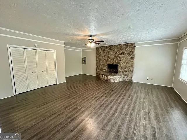 an empty room with wooden floor a fireplace and windows