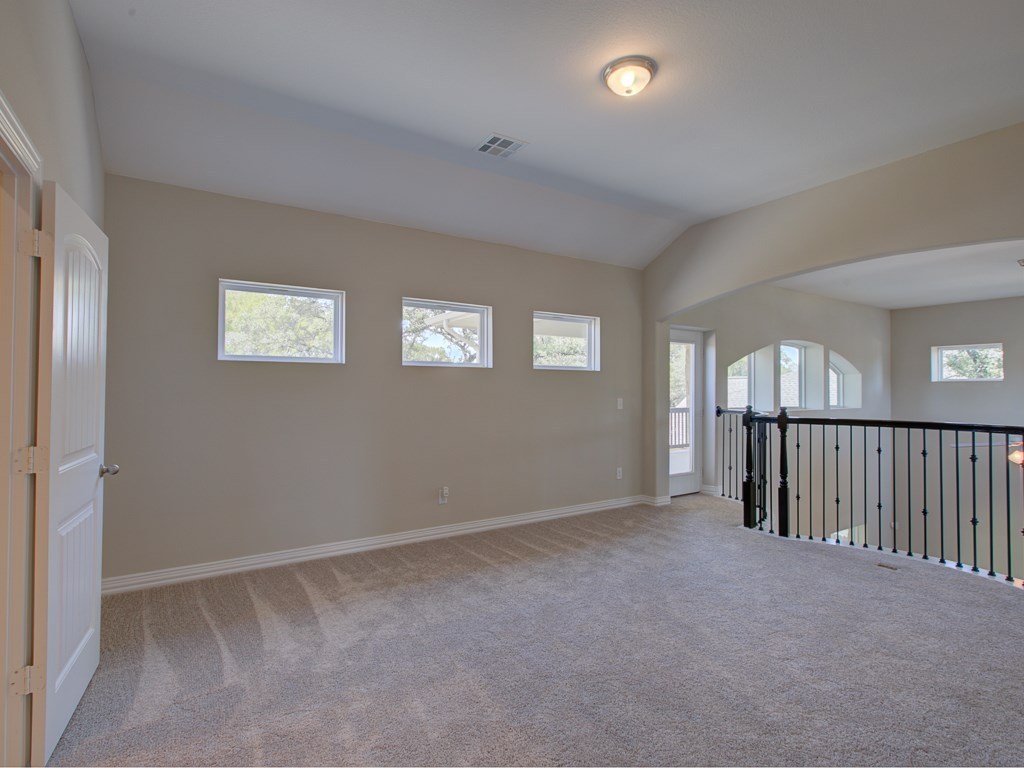 4303 Logan Ridge Drive Cedar Park, TX 78613 - Photo 19 of 24 Carpeted loft area with vaulted ceilings and a white paneled door