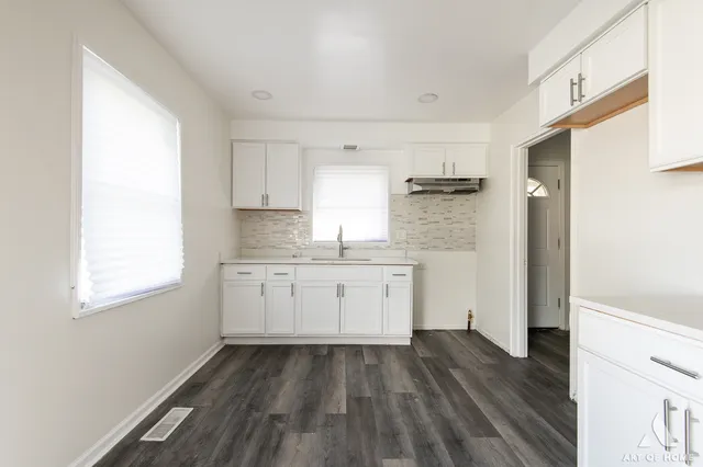 a kitchen with granite countertop white cabinets and wooden floor