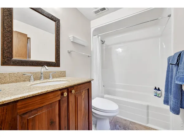 a bathroom with a granite countertop sink toilet a large mirror a bathtub and shower