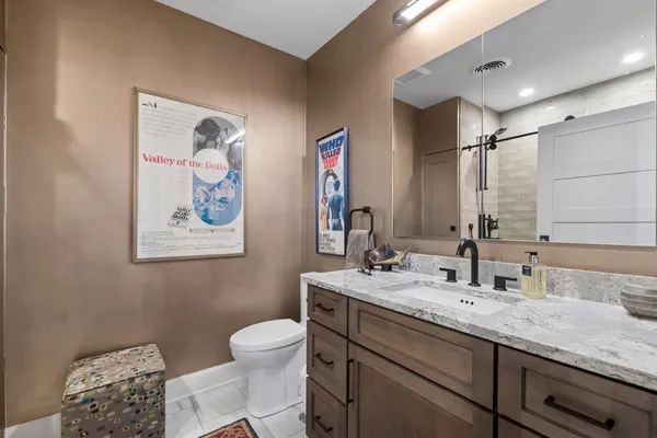 a bathroom with a granite countertop sink mirror vanity and toilet