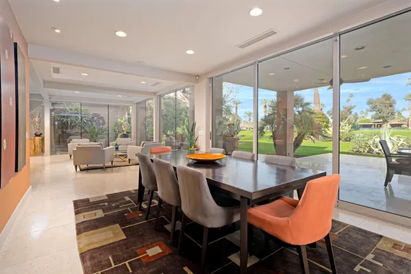 a dining room with glass top table and chairs