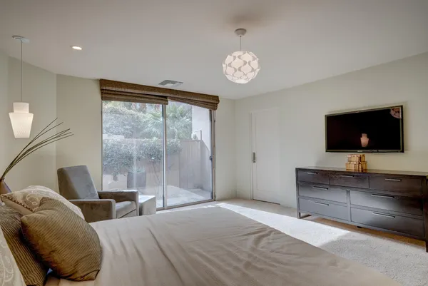 a bedroom with a bed and a flat screen tv on dresser