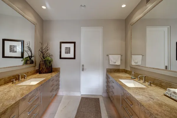 a bathroom with a granite countertop double vanity sink a mirror and a bathtub