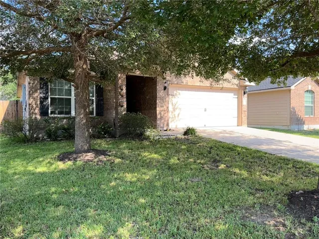 front view of a house with a yard and an trees