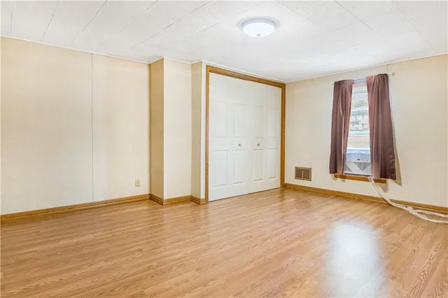 an empty room with wooden floor and windows with curtains
