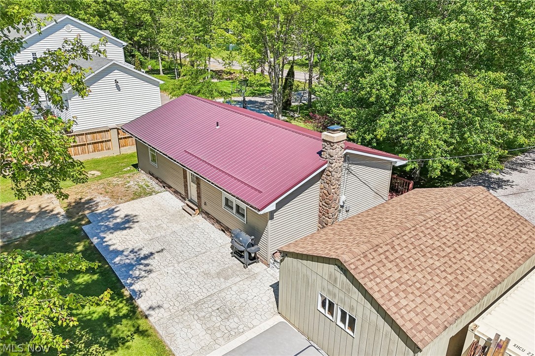 2960 Rome Rock Creek Road Rock Creek, OH 44084 - Photo 15 of 49 Property exterior featuring a red metal roof, light gray siding, and a stone chimney
