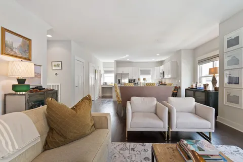 a living room with furniture a wooden floor and kitchen view
