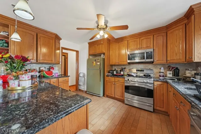 a kitchen with stainless steel appliances granite countertop a sink dishwasher stove top oven and refrigerator with wooden floor