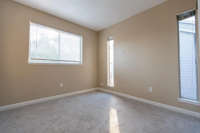 a view of an empty room with window and bathroom
