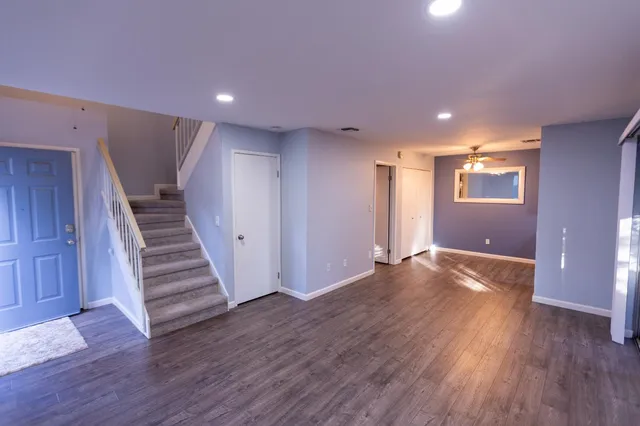 a view of an empty room with wooden floor and stairs