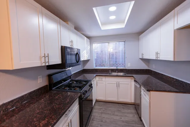 a kitchen with stainless steel appliances granite countertop a stove a sink and a microwave
