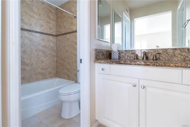 a bathroom with a granite countertop sink a toilet and shower
