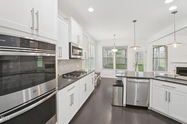 a white kitchen with granite countertop a stove and a sink