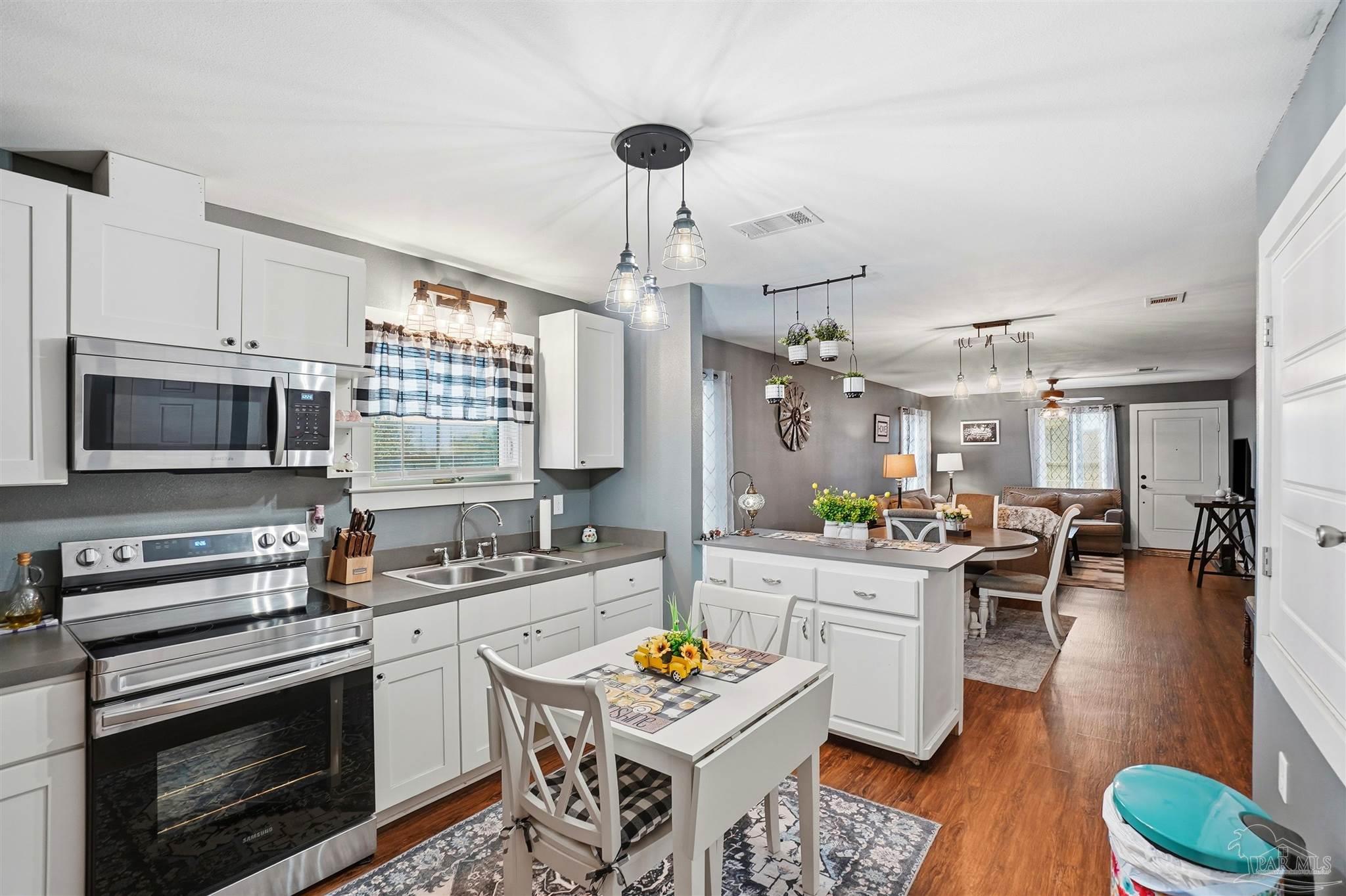 402 Front Street Century, FL 32535 - Photo 10 of 48 a kitchen with stainless steel appliances a stove a sink dishwasher a dining table and chairs with wooden floor