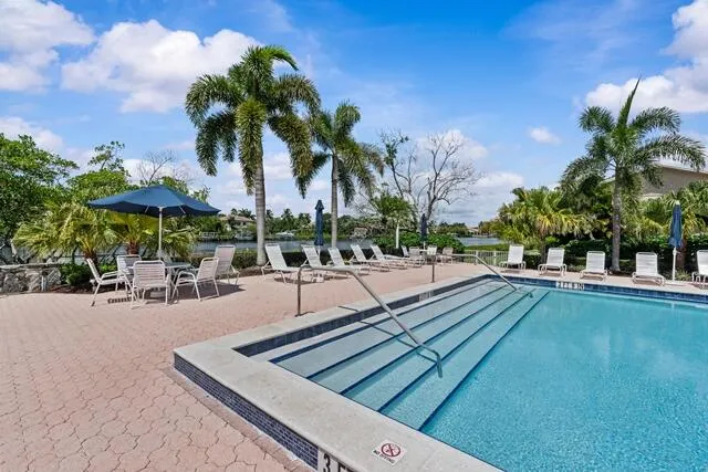 a view of swimming pool with outdoor seating and trees in the background