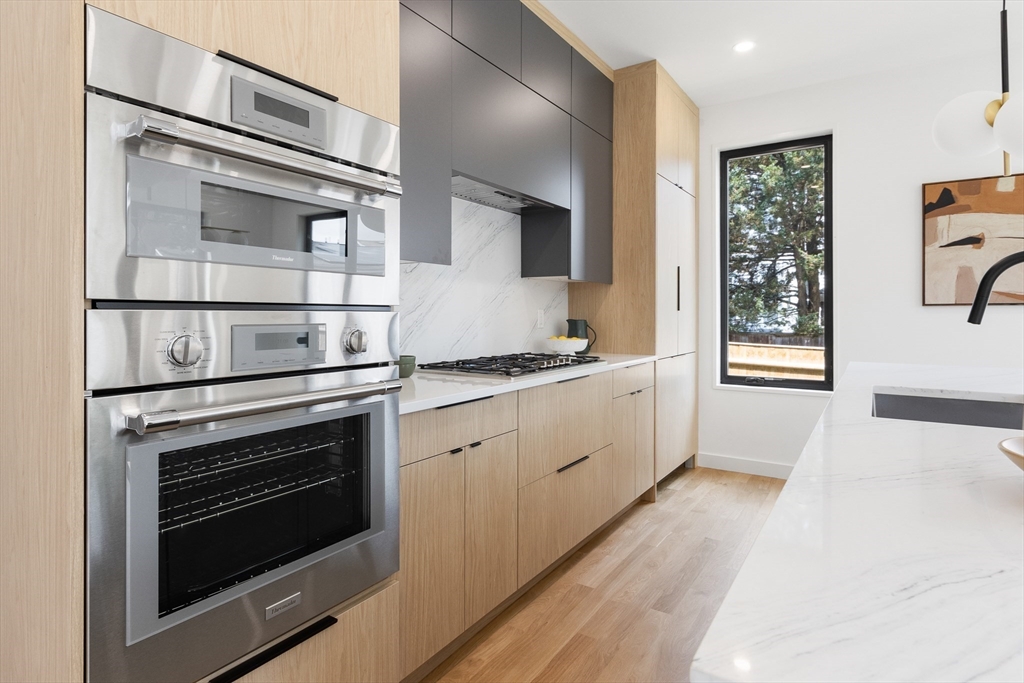 22 Appleton Street, Unit 1 Waltham, MA 02453 - Photo 9 of 36 a kitchen with granite countertop cabinets stainless steel appliances and wooden floor