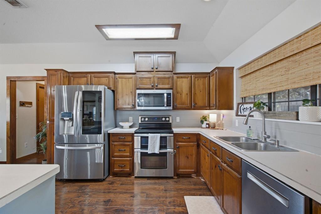 950 Johnson Bend Road Weatherford, TX 76088 - Photo 14 of 40 Wood-finish flooring, stainless steel appliances, wood cabinetry, white countertops, and a skylight